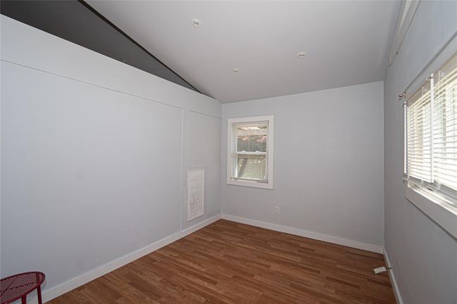 Empty room with lofted ceiling and wood finished floors | Image 7