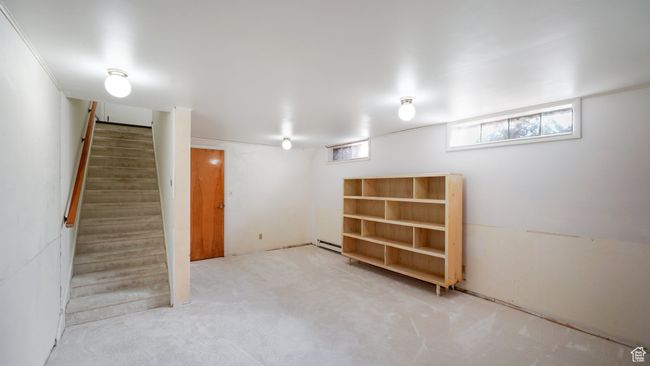 Basement featuring a baseboard heating unit, stairs, and carpet | Image 16