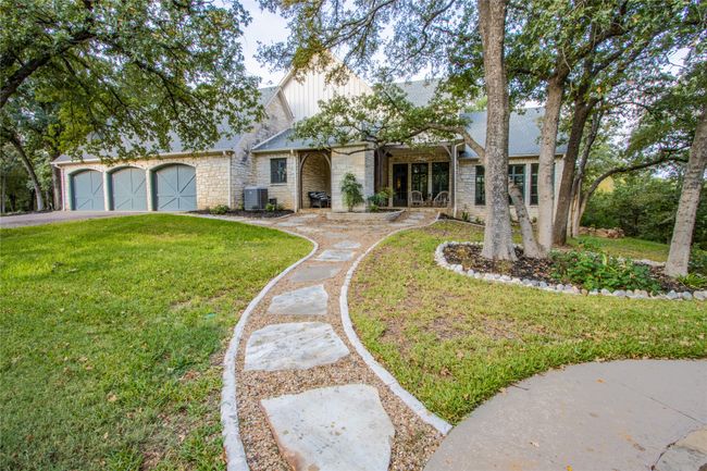 View of front of house with stone siding, central air condition unit, an attached garage, a front lawn, and driveway | Image 29