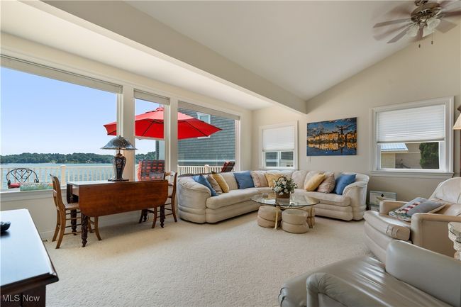 Living room with plenty of natural light, vaulted ceiling, a ceiling fan, carpet floors, and a water view | Image 6