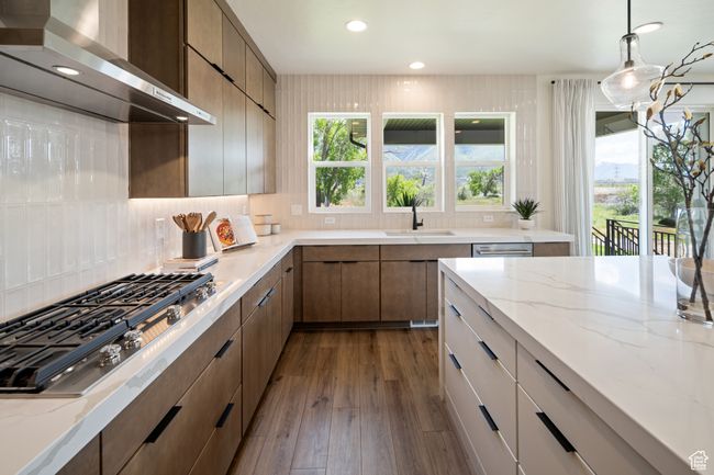 Kitchen with wall chimney range hood, a sink, stainless steel gas stovetop, backsplash, and recessed lighting | Image 13