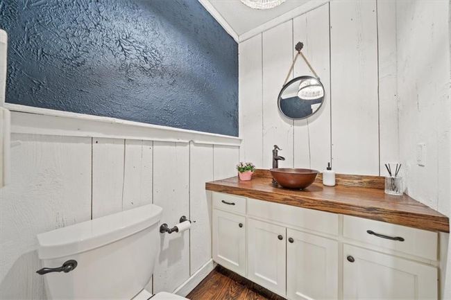 Half bath with toilet, wood finished floors, vanity, and a decorative wall | Image 12