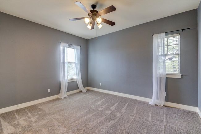 Secondary bedroom with walk-in closet, carpet, a wealth of natural light, and a ceiling fan | Image 25