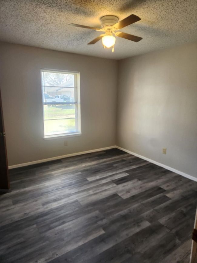 Empty room featuring a ceiling fan, baseboards, dark wood finished floors, and a textured ceiling | Image 17