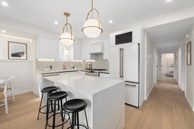 Kitchen with premium range hood, high end appliances, light wood-style floors, and a center island | Image 7