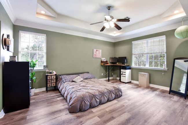 Bedroom featuring a tray ceiling, recessed lighting, wood finished floors, ornamental molding, and a desk | Image 16