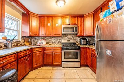 Kitchen featuring light tile patterned floors, stainless steel appliances, light stone countertops, and sink | Image 3