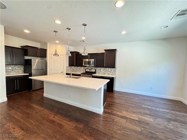 Kitchen with stainless steel appliances, tasteful backsplash, recessed lighting, a kitchen island with sink, and light countertops | Image 6