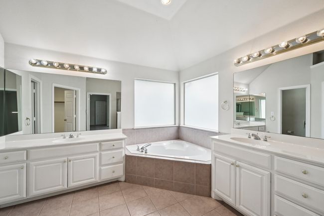 Bathroom featuring a garden tub, light tile patterned flooring, two vanities, and lofted ceiling | Image 13