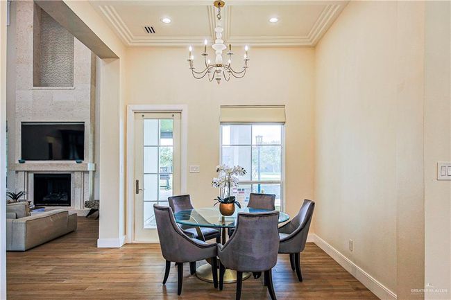 Dining area with a chandelier, ornamental molding, porcelain floors, a fireplace, and recessed lighting | Image 25