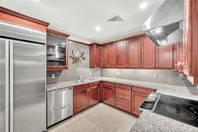 This spacious Kitchen is not your typical condo tiny Kitchen. Abundant storage in Brookhaven cabinetry with granite countertops & backsplash. There is also a Walk-In Pantry. Sure to please the Chef or Foodie in your home! | Image 5