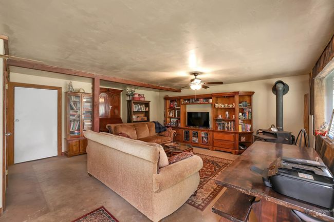 Living area with a wood stove, finished concrete floors, and ceiling fan | Image 39