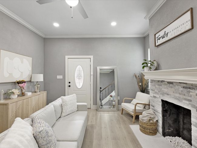 Living room with light wood-type flooring, a fireplace, ceiling fan, crown molding, and stairs | Image 8