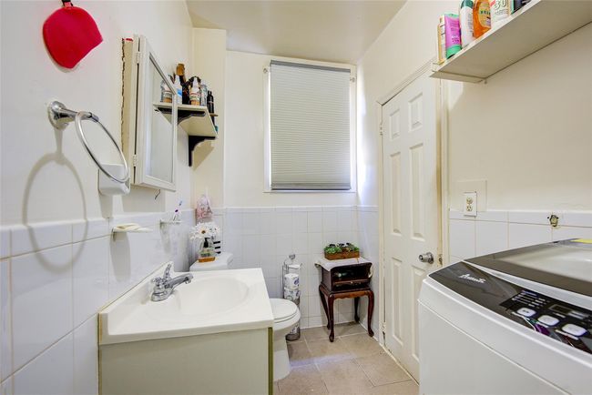 Bathroom featuring tile walls, washer / clothes dryer, tile patterned floors, vanity, and a wainscoted wall | Image 23