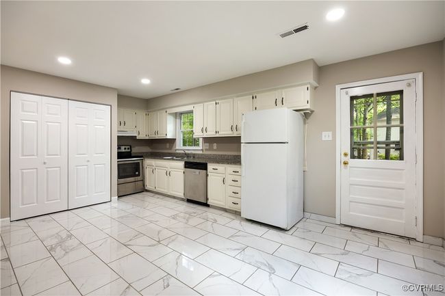 Kitchen with stainless steel appliances, light marble finish flooring, dark countertops, recessed lighting, and under cabinet range hood | Image 9