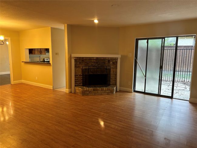 Unfurnished living room featuring wood finished floors, a fireplace with raised hearth, and a chandelier | Image 8