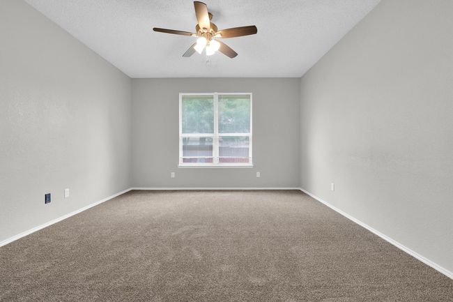 Carpeted empty room with a ceiling fan, baseboards, and a textured ceiling | Image 17