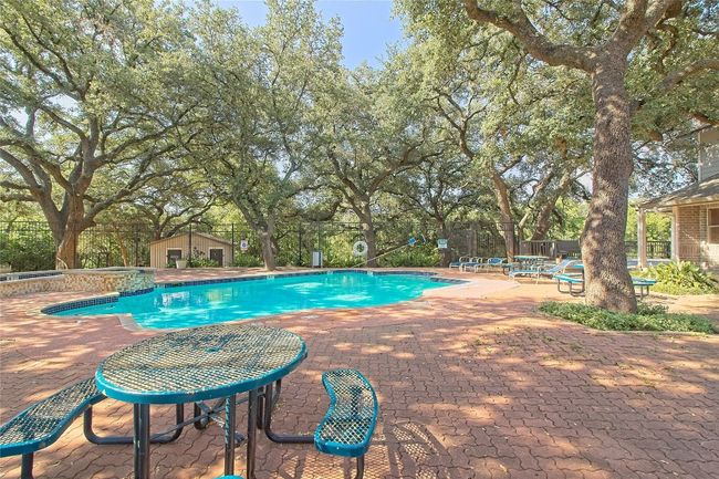 Community pool with a patio and view of scattered trees | Image 6