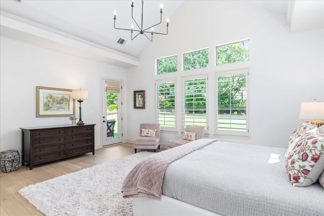 Bedroom with access to exterior, wood finished floors, high vaulted ceiling, and a chandelier | Image 17