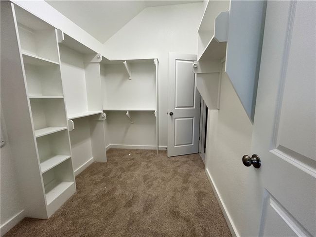 Primary Walk in closet featuring carpet flooring and vaulted ceiling | Image 11
