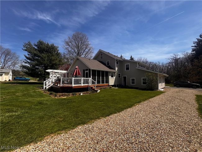 Rear view of house featuring a sunroom, a deck, a lawn, and gravel driveway | Image 38
