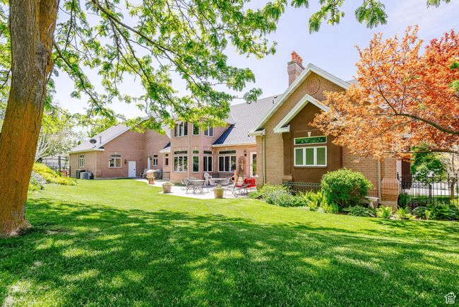 Rear view of house featuring brick siding, a lawn, a patio area, and a chimney | Image 98
