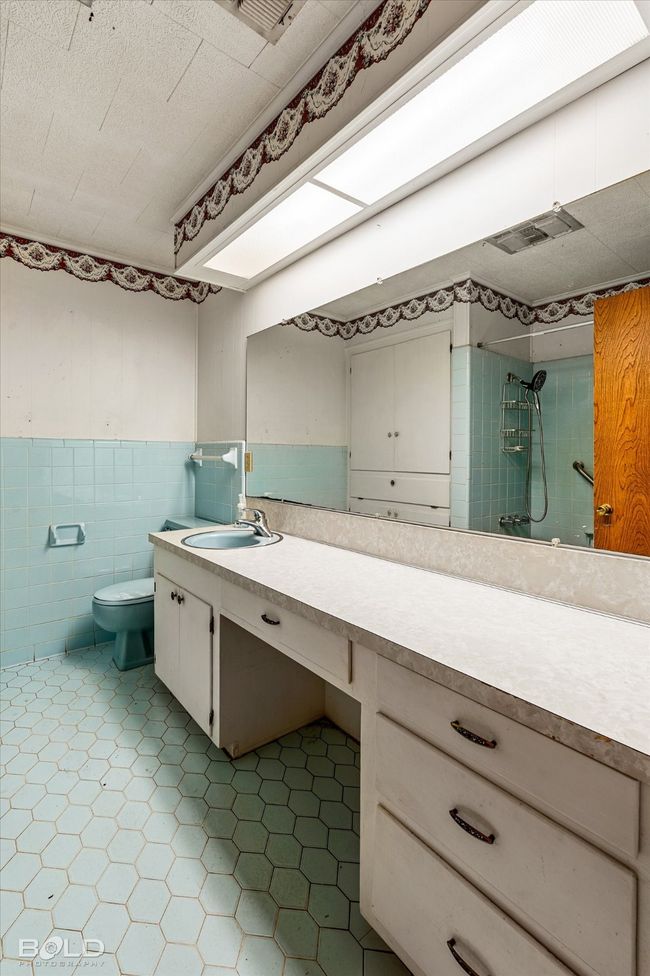 Bathroom with vanity, a shower, a wainscoted wall, tile walls, and tile patterned flooring | Image 22