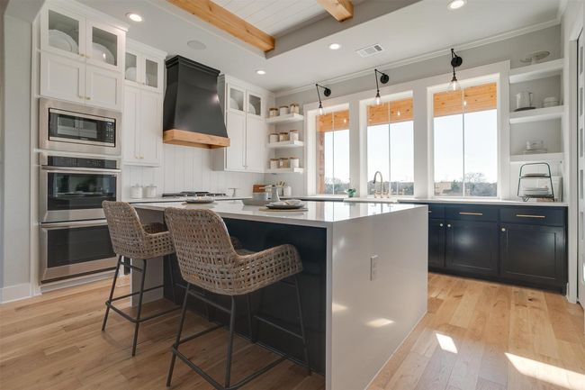 Kitchen with white cabinets, a center island, stainless steel appliances, and custom exhaust hood | Image 11