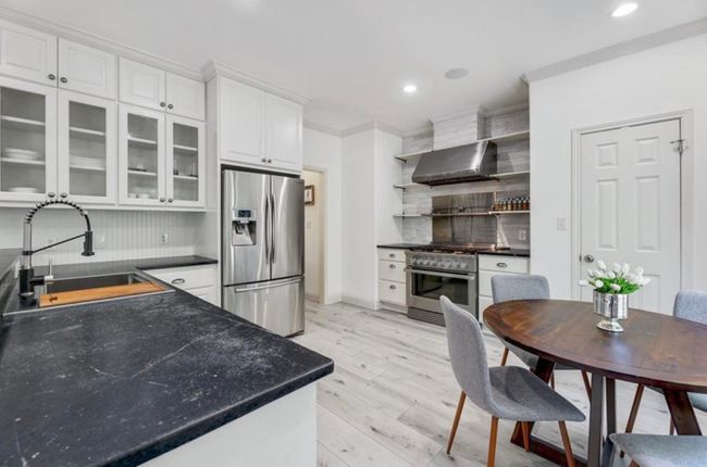 Kitchen with a sink, open shelves, white cabinetry, appliances with stainless steel finishes, and wall chimney range hood | Image 13