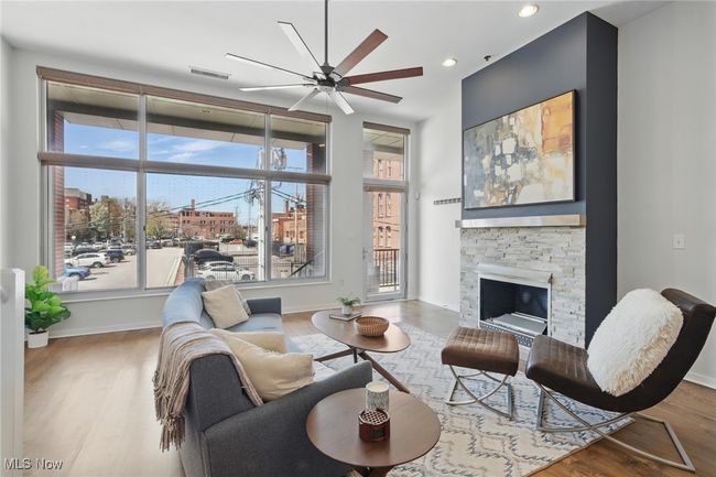Living area featuring a ceiling fan, wood finished floors, visible vents, and a fireplace | Image 5