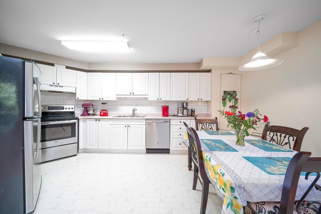 Kitchen with appliances with stainless steel finishes, under cabinet range hood, a sink, light countertops, and decorative backsplash | Image 21