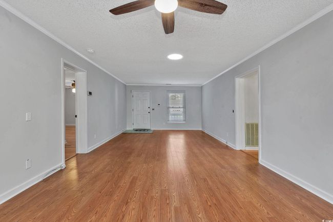 Unfurnished living room with ceiling fan, light hardwood / wood-style flooring, crown molding, and a textured ceiling | Image 11