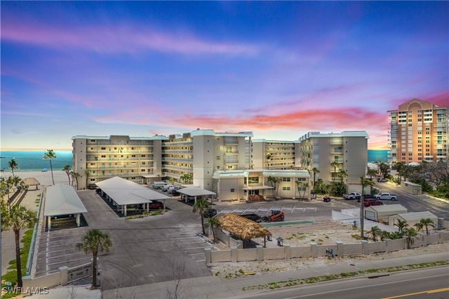 At dusk, the building’s exterior is bathed in golden sunset hues, while soft lighting creates a welcoming glow—offering a serene and elegant beachfront atmosphere. | Image 6