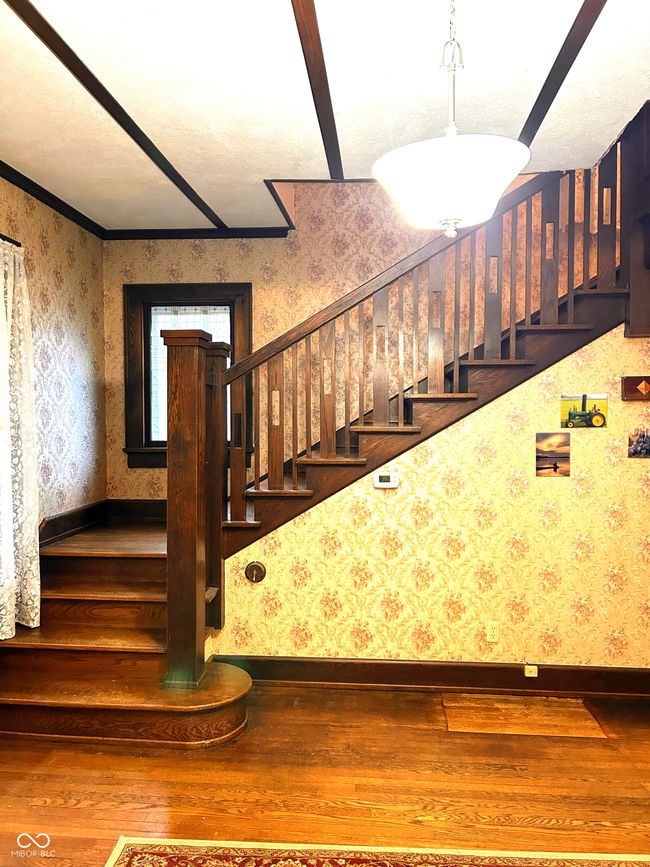 stairs featuring baseboards, wood finished floors, and wallpapered walls | Image 8