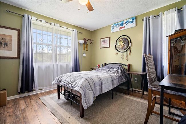 Bedroom featuring baseboards, a ceiling fan, a textured ceiling, and wood finished floors | Image 17