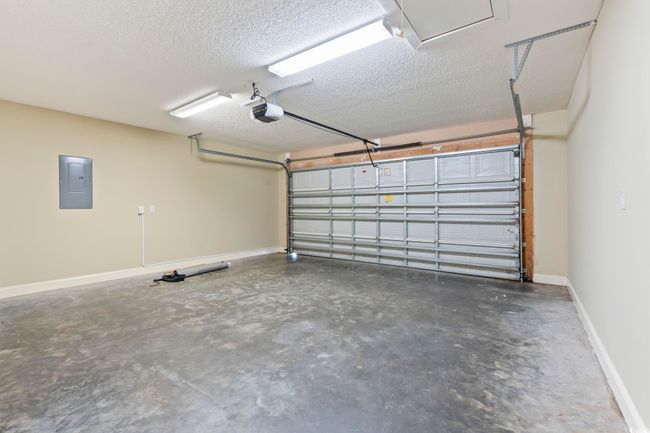 Garage with a garage door opener, electric panel, and baseboards | Image 25