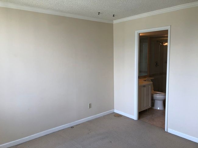 Unfurnished bedroom with crown molding, baseboards, carpet flooring, a textured ceiling, and ensuite bath | Image 15