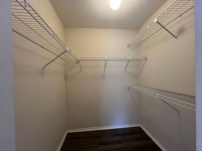 Walk in closet featuring dark wood-style floors | Image 23