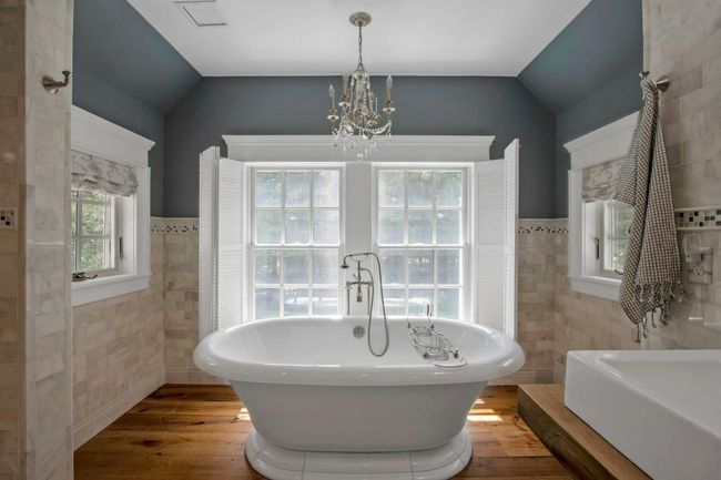 Bathroom featuring tile walls, vaulted ceiling, a chandelier, a soaking tub, and wood finished floors | Image 28