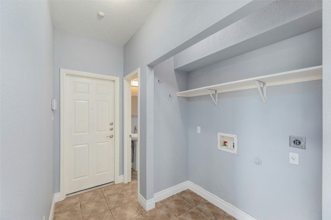 Washroom featuring electric dryer hookup, hookup for a washing machine, light tile patterned floors, and hookup for a gas dryer | Image 17