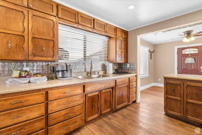 Kitchen with light countertops, a sink, backsplash, and brown cabinets | Image 26