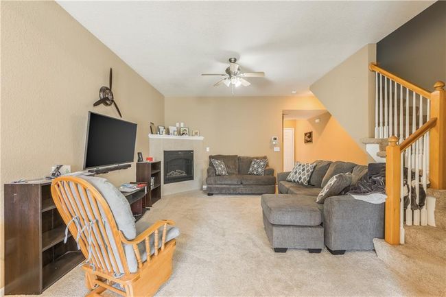 Carpeted living room featuring stairway, a fireplace, and ceiling fan | Image 5