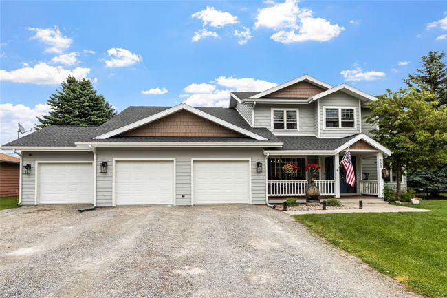 View of front of house featuring an attached garage, gravel driveway, covered porch, and roof with shingles | Image 58
