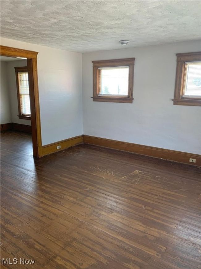 Empty room featuring dark wood finished floors and a textured ceiling | Image 8