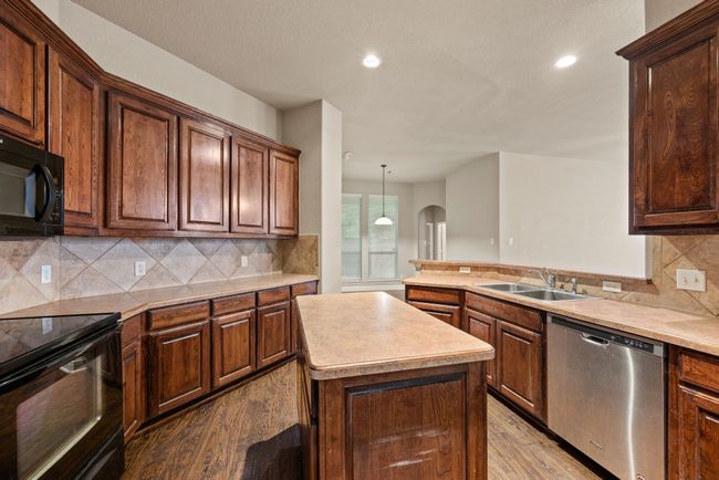 Kitchen featuring wood finished floors, a sink, black appliances, light countertops, and recessed lighting | Image 13