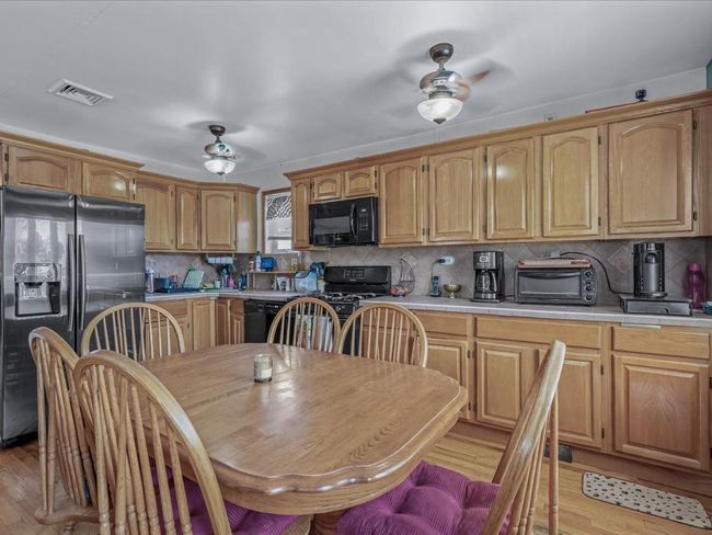 Kitchen featuring black appliances, a ceiling fan, light wood-style floors, and tile counters | Image 19