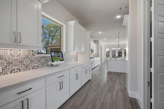 Kitchen featuring white cabinets, tasteful backsplash, recessed lighting, a sink, and baseboards | Image 5