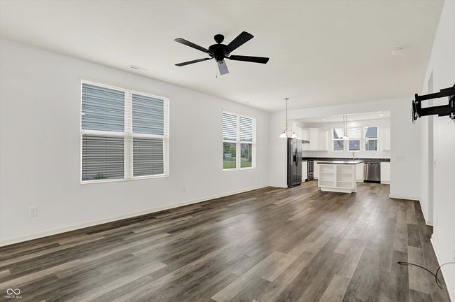 unfurnished living room featuring dark wood-style flooring, plenty of natural light, a chandelier, and ceiling fan | Image 5
