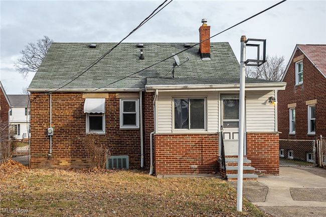 Rear view of property with entry steps, brick siding, and a chimney | Image 6