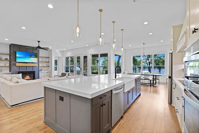 Kitchen with a sink, light wood-type flooring, a large fireplace, stainless steel appliances, and recessed lighting | Image 11